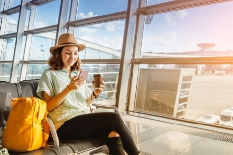 mujer en aeropuerto revisando como activar datos desde su telefono en el extranjero